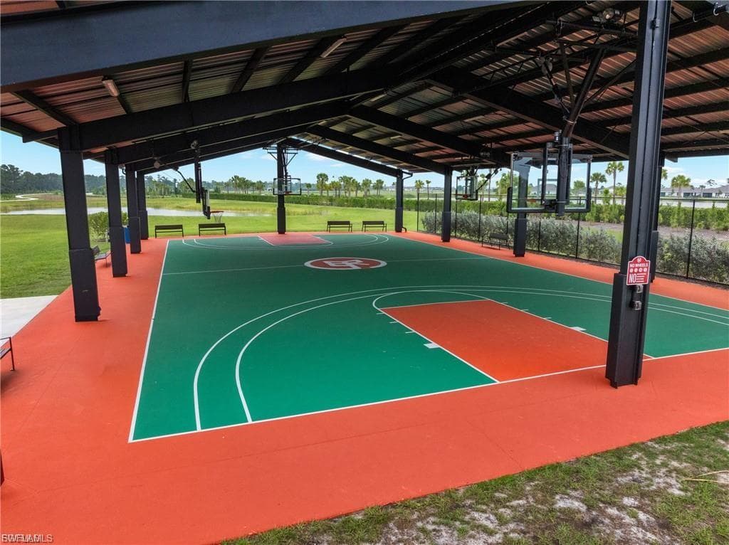 Covered sports court featuring a professional-grade multi-sport playing surface with contrasting green and red athletic flooring, crisp white court markings, and sturdy steel support columns