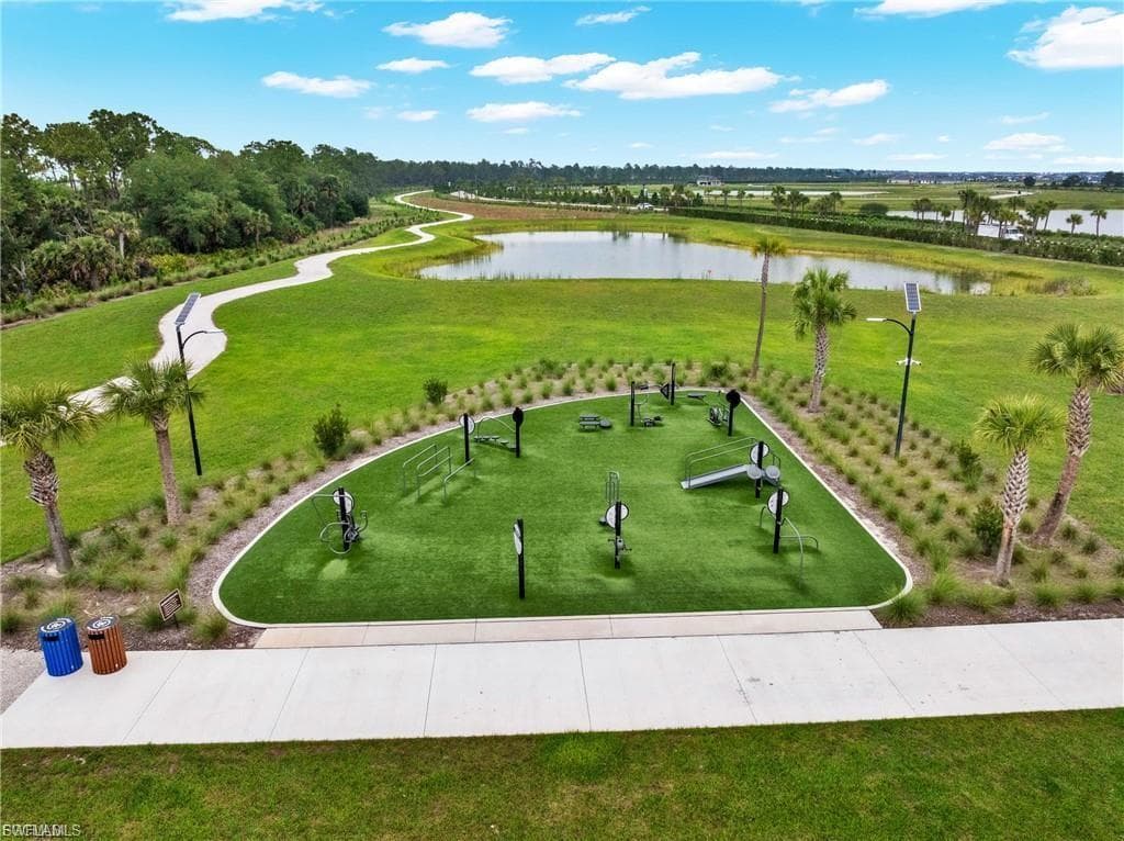 Expansive recreational grounds featuring meticulously manicured lawn, curved concrete hardscape pathway, strategically placed landscape lighting, and mature palmetto plantings