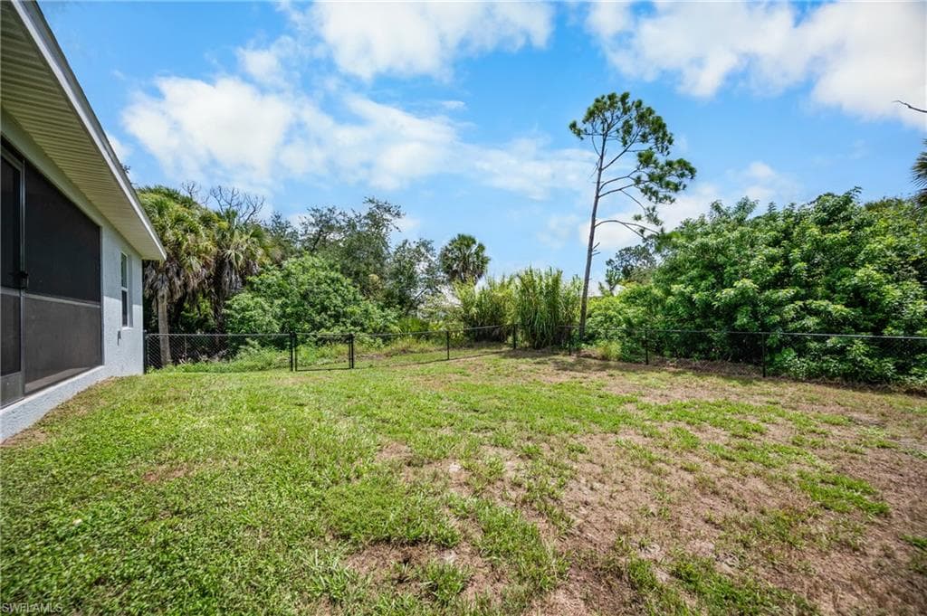 Fenced rear yard with expansive green space and mature natural landscaping