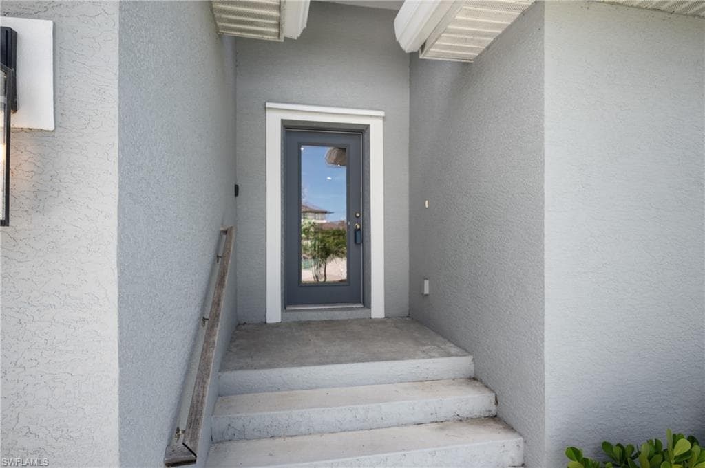 Entryway featuring concrete steps, stucco exterior, and a glass-paneled door