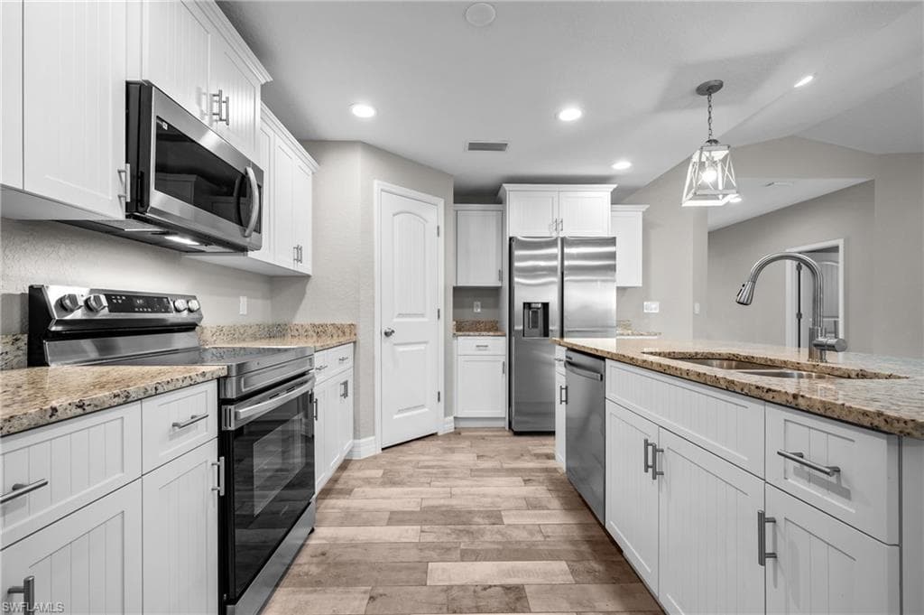 Kitchen featuring white cabinetry, stainless steel appliances, granite countertops, wood-finish flooring, and recessed lighting
