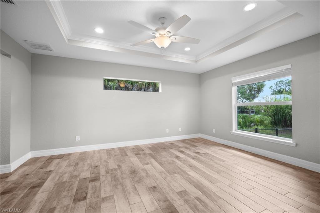 Wood-finish flooring, tray ceiling, recessed lighting, and a ceiling fan