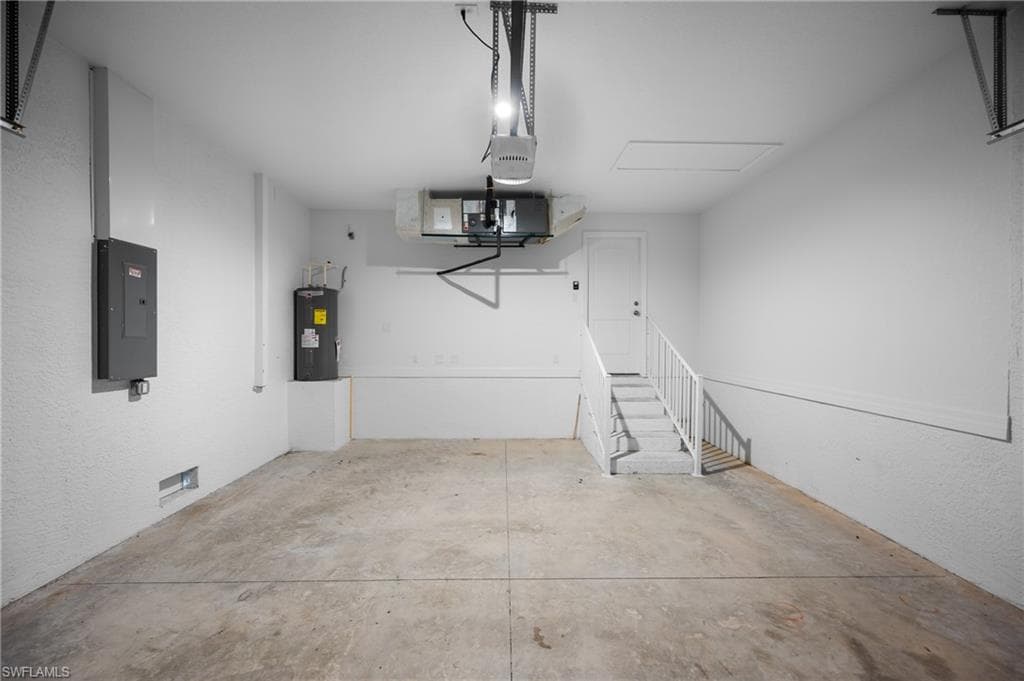 Spacious garage with a concrete floor, built-in staircase with a handrail, and an overhead garage door opener