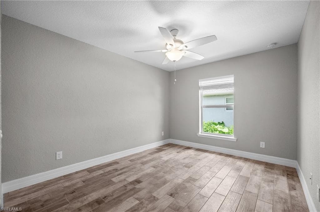 Wood-finish flooring, white trim, recessed lighting, ceiling fan, and textured walls