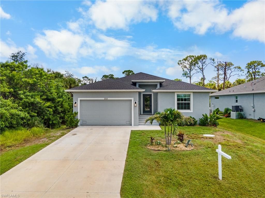 Contemporary exterior with a covered entry, attached garage, concrete driveway, and established landscaping