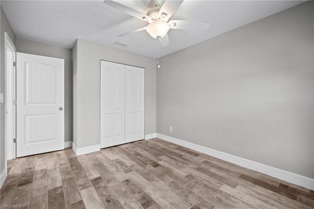 Wood-finish flooring, ceiling fan with integrated lighting, bi-fold closet doors, and a paneled interior door