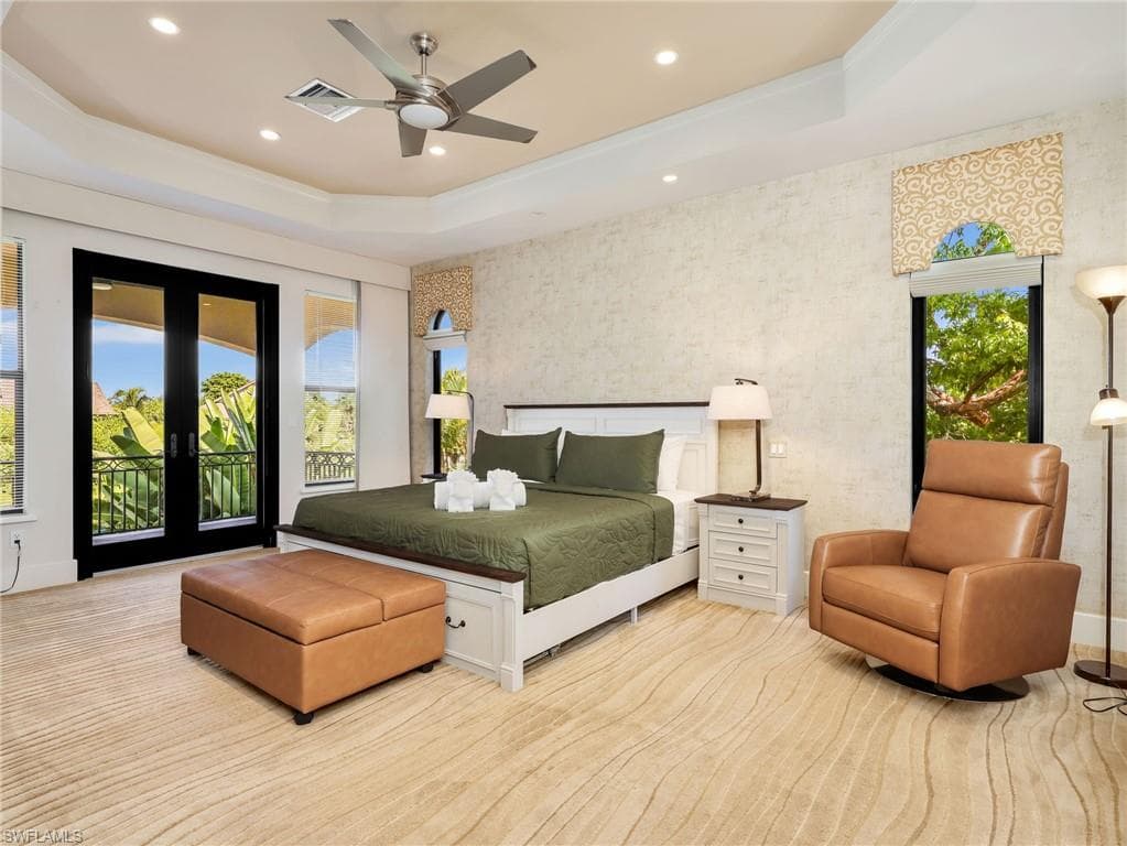 Tray ceiling with recessed lighting and ceiling fan, direct access to an outdoor balcony, white wood-frame bed with built-in storage, textured wall finishes, and wood-finish flooring