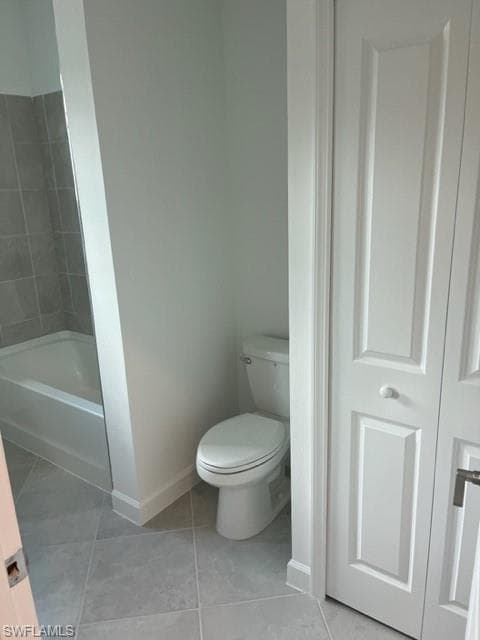 Bathroom with baseboards, toilet, tile patterned floors, and tub / shower combination