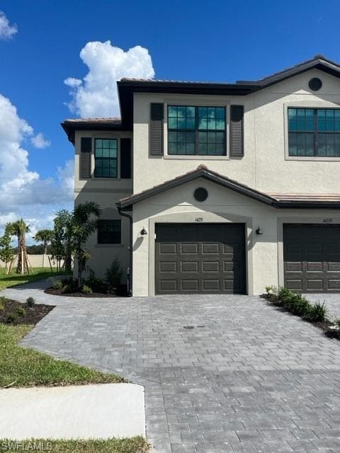 View of front of house featuring stucco siding, an attached garage, and decorative driveway