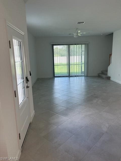 Unfurnished room featuring baseboards, stairs, ceiling fan, and light tile patterned flooring