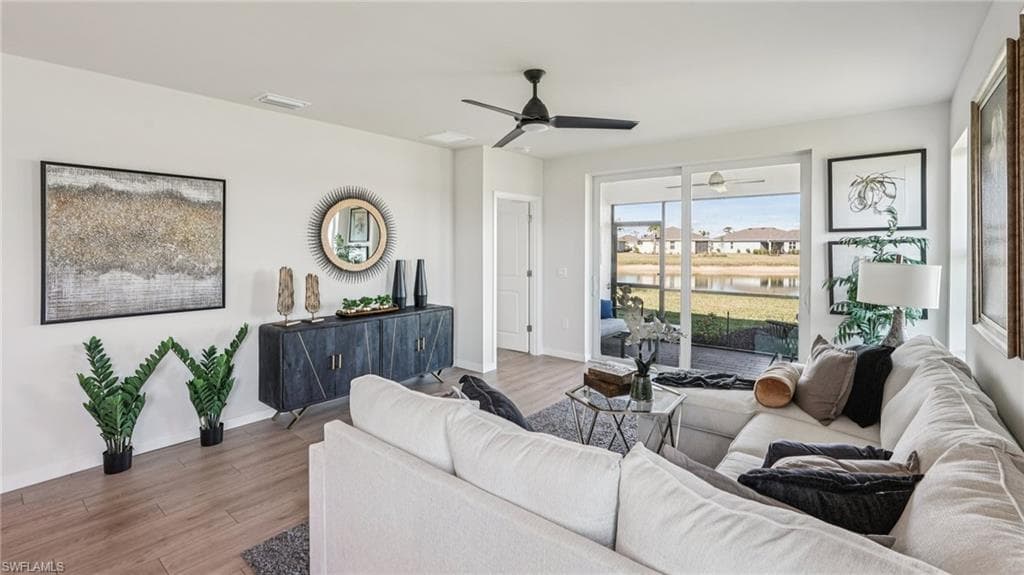 Spacious living area featuring wood-finish flooring, a ceiling fan, and sliding glass doors leading to an enclosed outdoor space