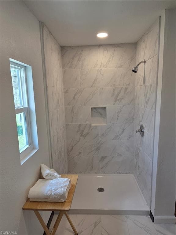 Tiled shower featuring a recessed niche, chrome shower head, chrome control handle, and a single window