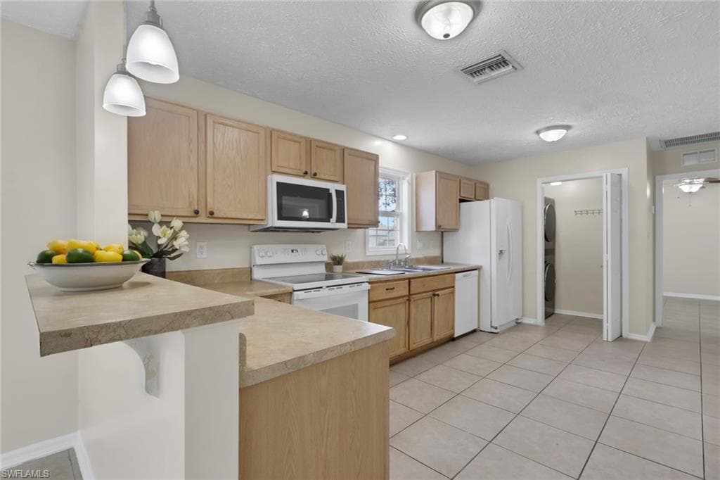 Bright kitchen featuring wood-finish cabinetry, tile flooring, and a spacious island with extended countertop seating