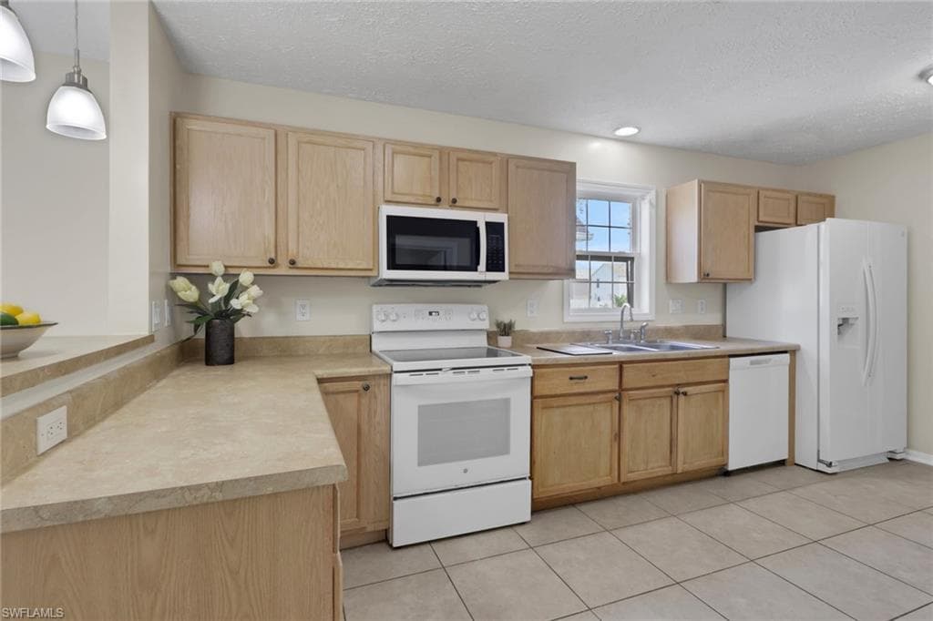 Kitchen featuring wood-finish cabinetry, solid surface countertops, a white appliance package, and tile flooring