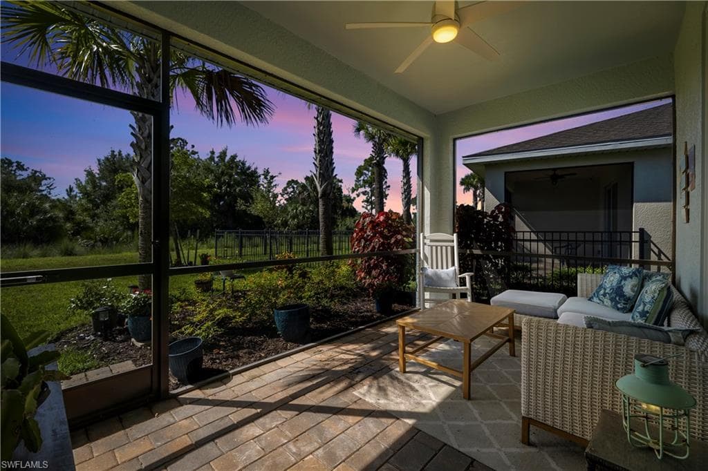 Screened patio with a ceiling fan, paver flooring, and landscaped garden area