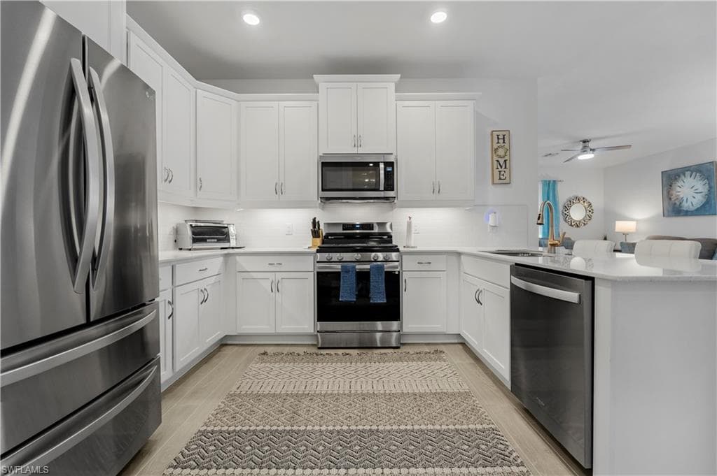 Kitchen featuring white cabinetry, stainless steel appliances, and light-toned countertops