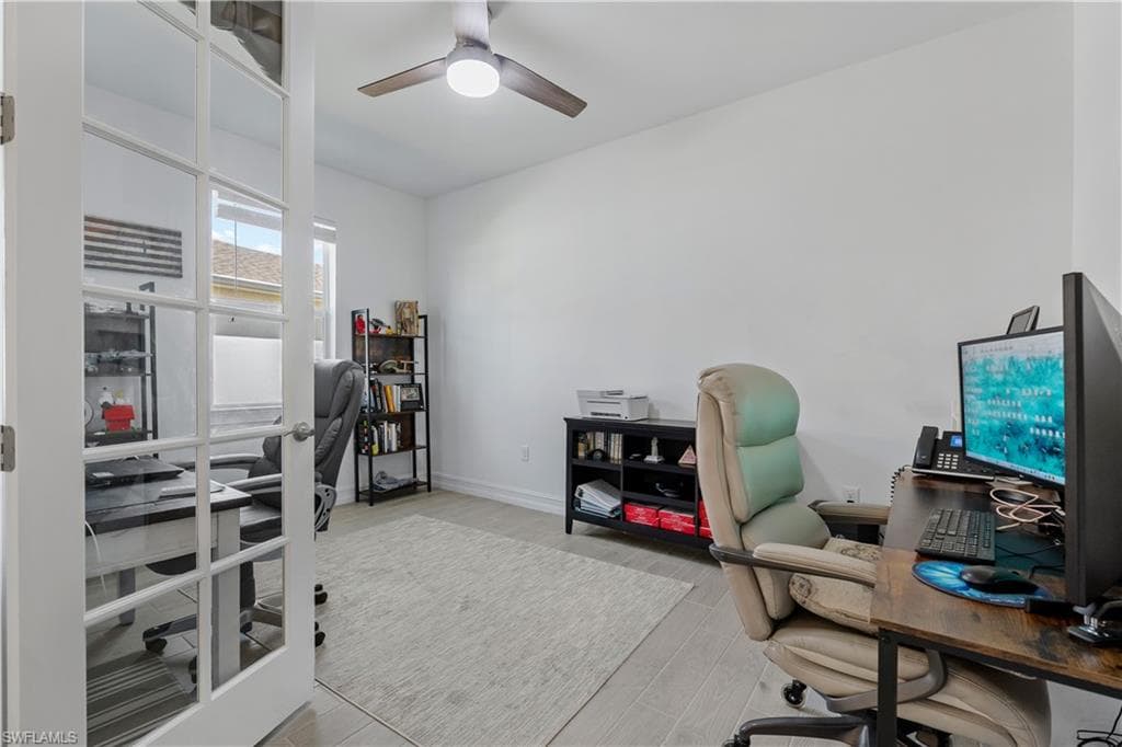 Room featuring French doors, a ceiling fan with integrated lighting, two windows, and light-toned flooring