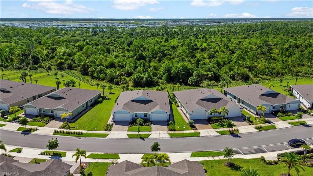 Aerial view showcasing a modern residential community with contemporary architectural design, manicured landscaping, and mature tree-lined surroundings