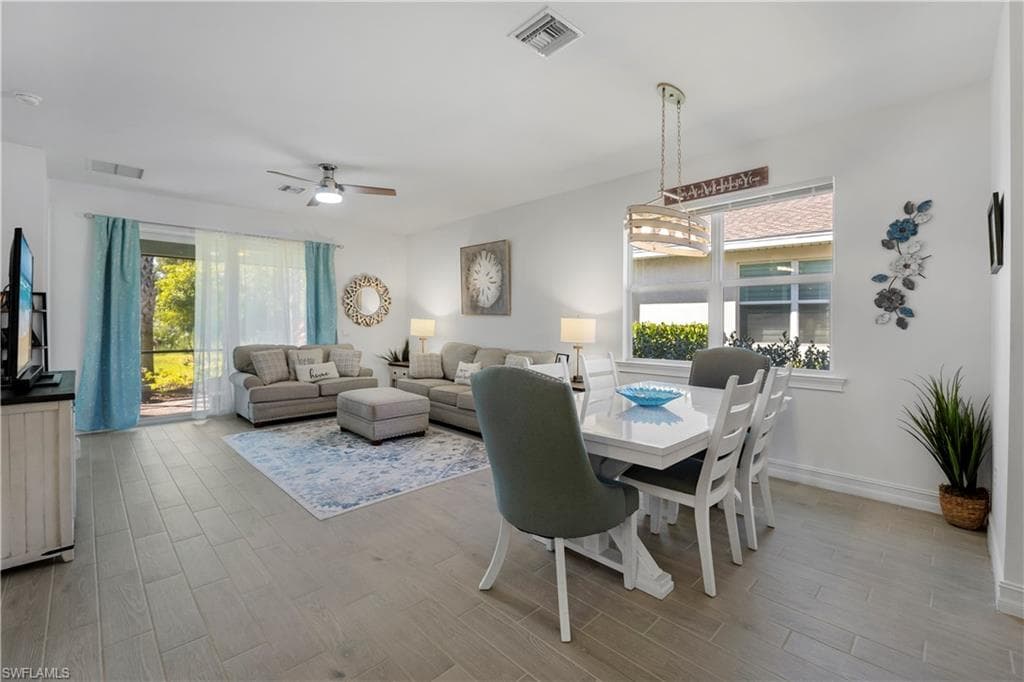 Open-concept design featuring wood-finish flooring, a ceiling fan, and a dining area with a linear chandelier