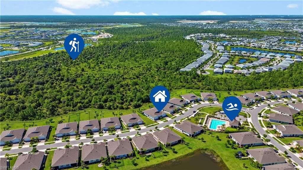 Aerial community perspective featuring residential properties, a central swimming pool with adjacent paved sun deck, and a natural preserve area