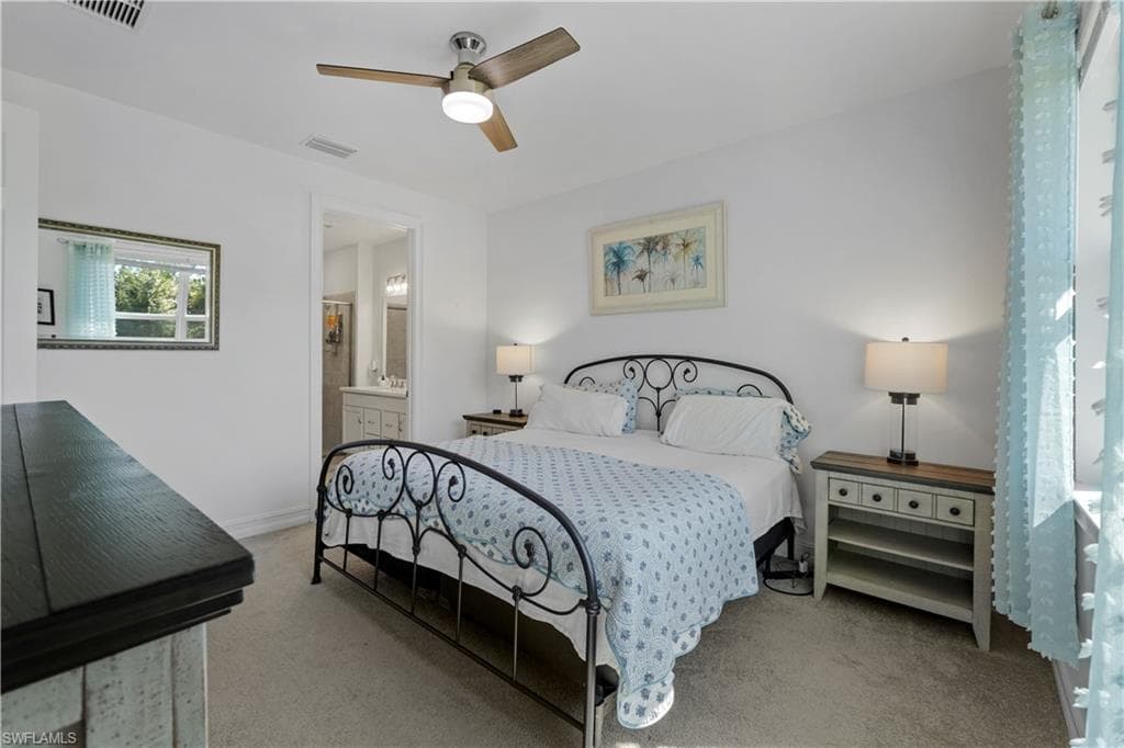Ceiling fan with integrated lighting, carpeted flooring, window with vertical blinds, built-in shelving, and an open doorway to an adjoining bathroom