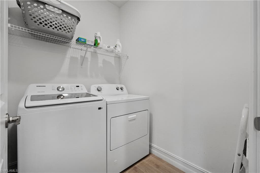 Dedicated laundry room featuring a Samsung top-load washer and electric dryer with convenient upper shelving for storage