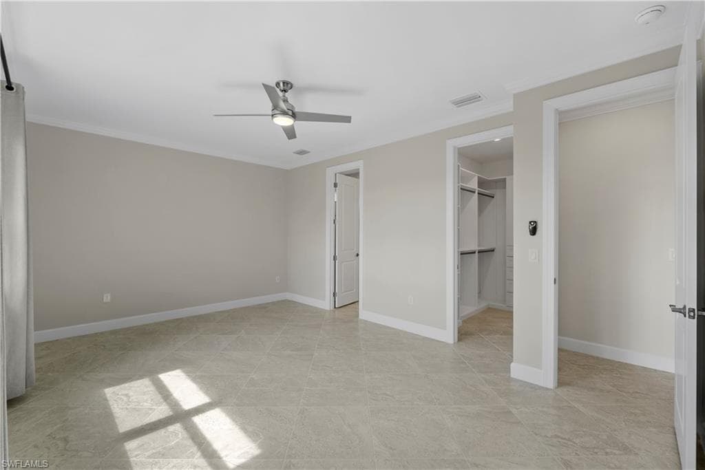 Spacious room featuring tile flooring, a modern ceiling fan, and access to a built-in closet system