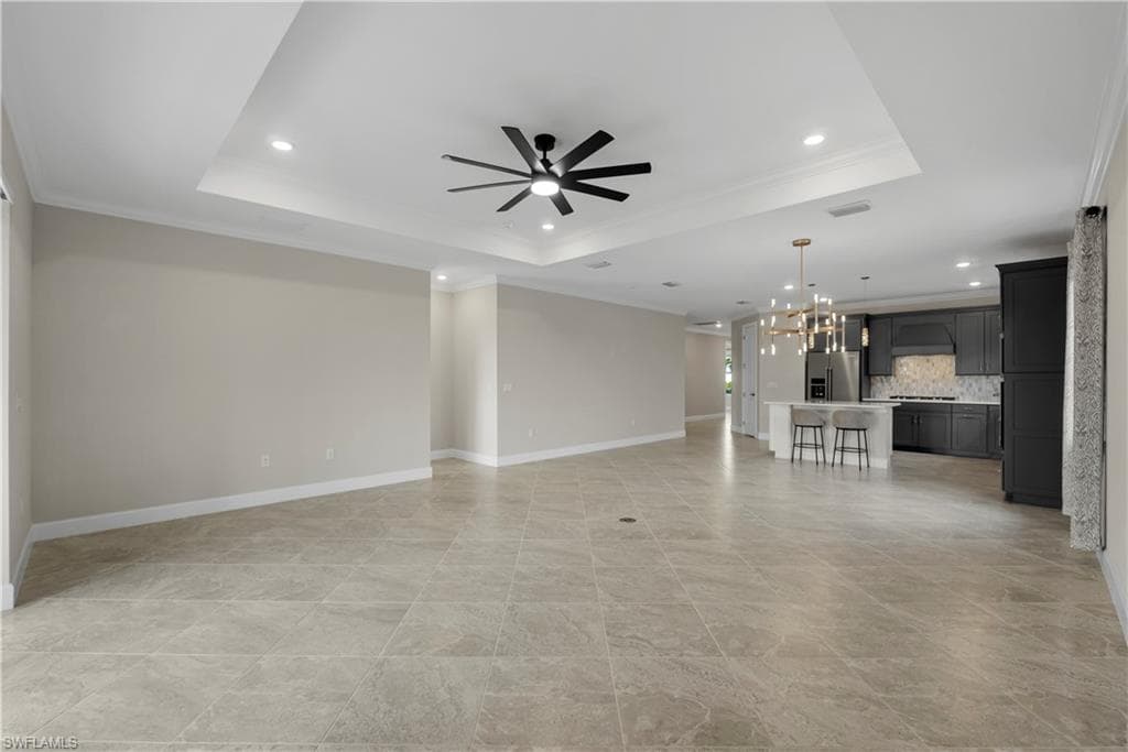 Expansive tiled flooring complemented by a tray ceiling with recessed lighting and a ceiling fan