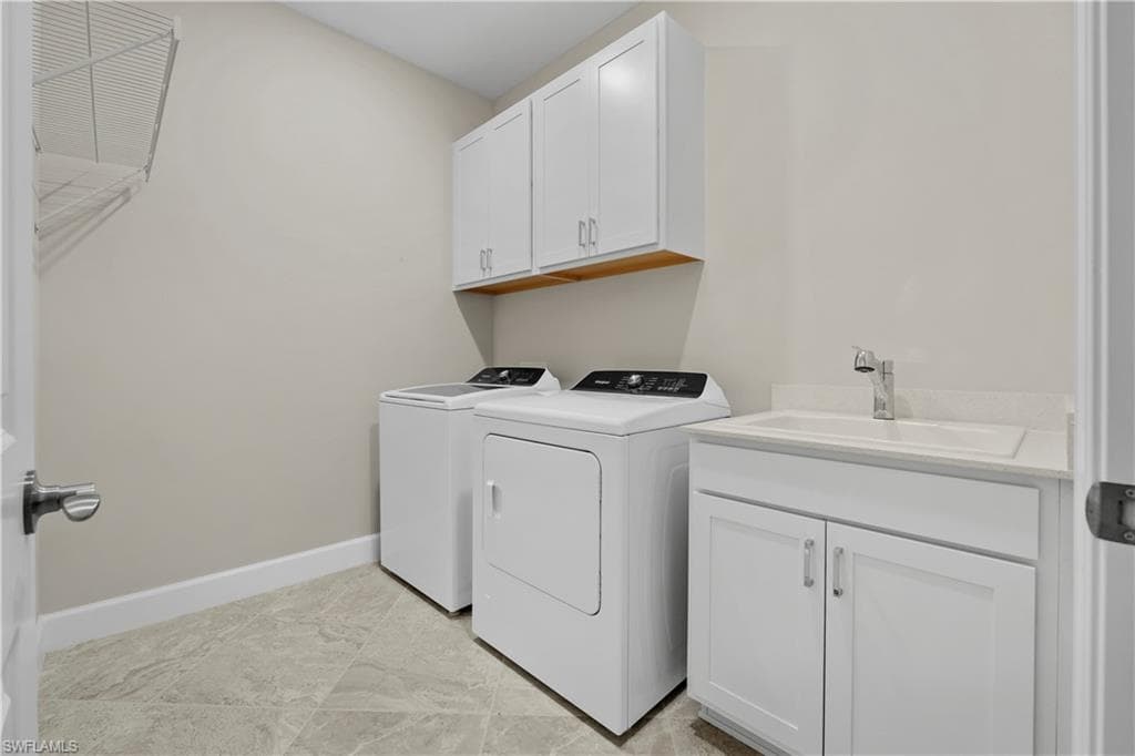 Laundry area featuring white cabinetry, a utility sink with a chrome faucet, and gray-toned tile flooring