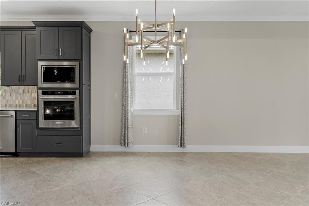 Gray shaker-style cabinetry with stainless steel appliances, tiled backsplash, and light-toned flooring