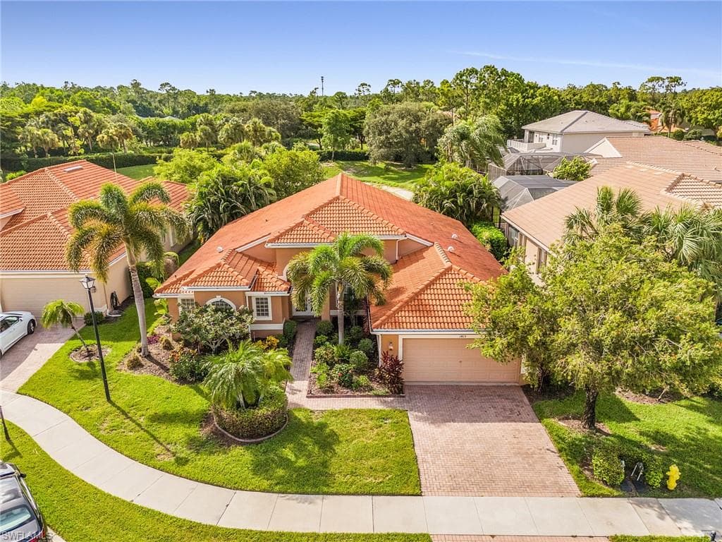 Terracotta tile roofing, stucco exterior, paver driveway, mature landscaping, and a concrete sidewalk