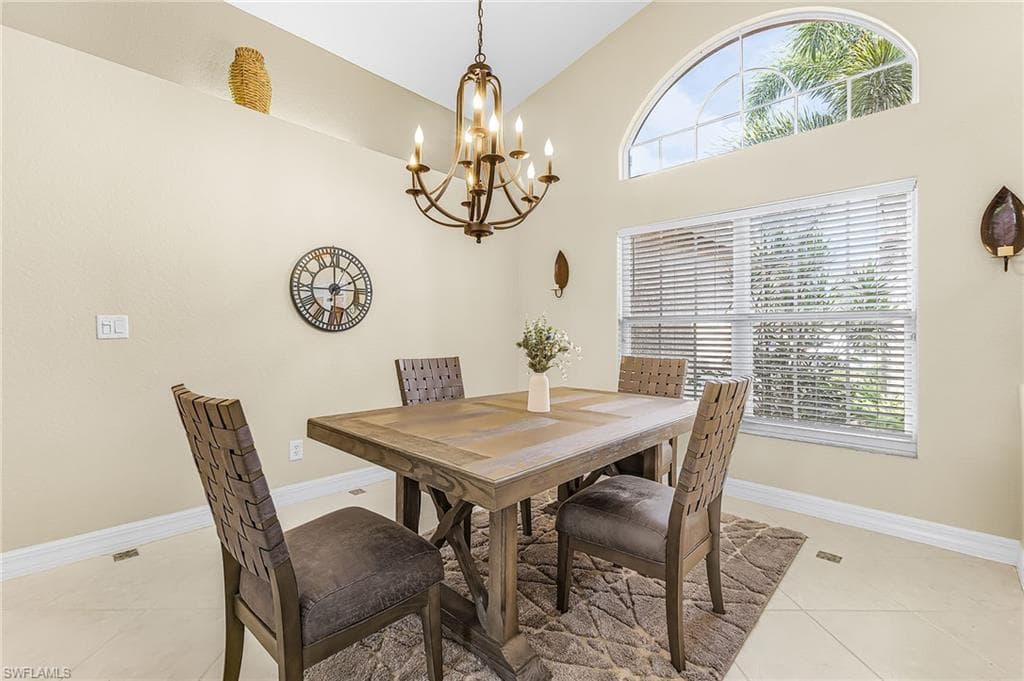 Vaulted ceiling with an ornate chandelier, arched transom window, and tiled flooring