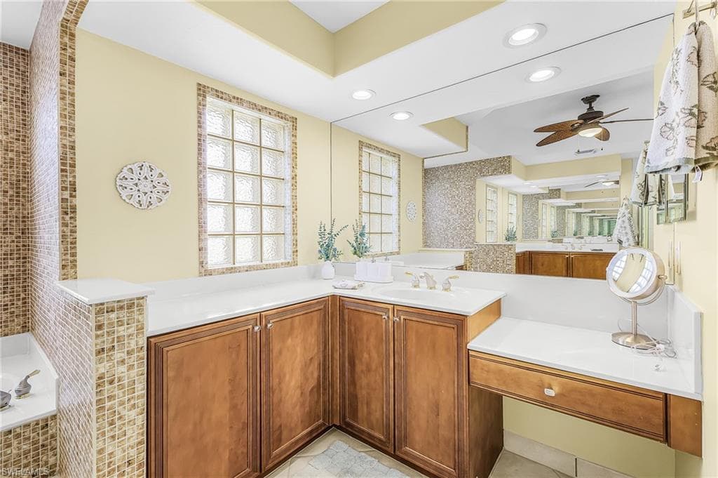 Expansive vanity with a light-toned countertop, wood-finish cabinetry, and an integrated makeup desk
