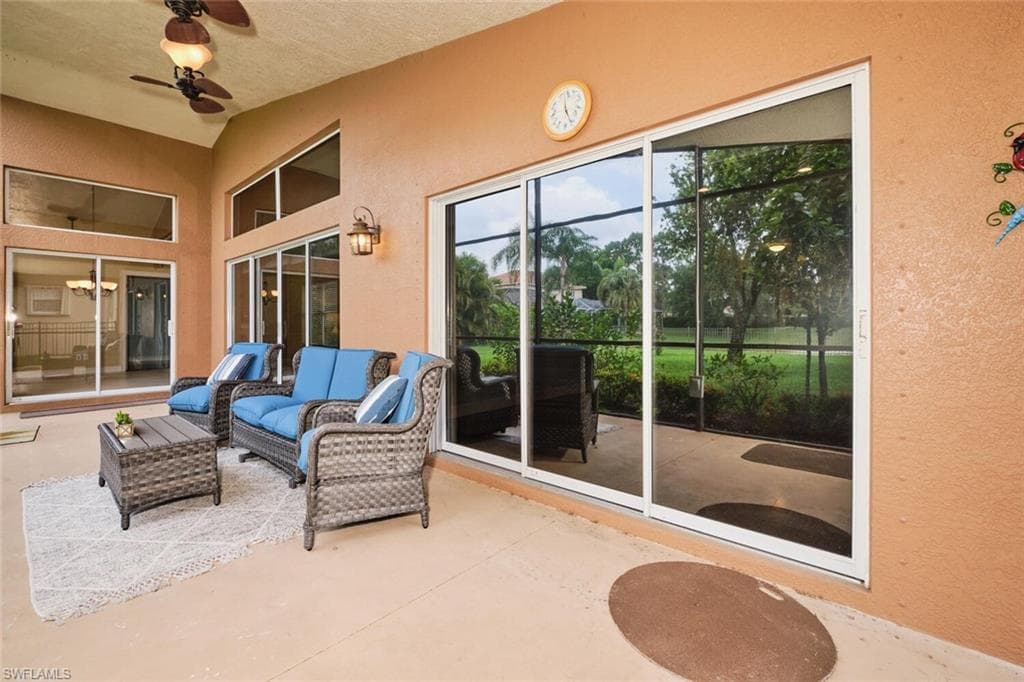 Covered outdoor patio with a ceiling fan, vaulted ceiling, exterior wall lantern, and multiple sliding glass doors