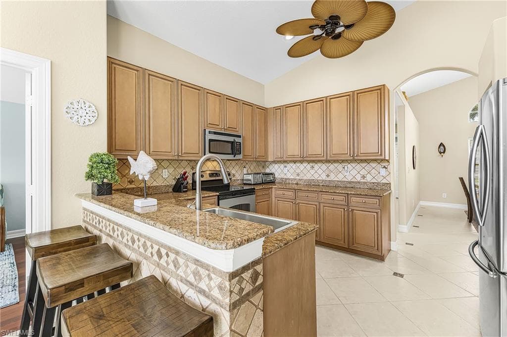 Kitchen featuring wood cabinetry, stainless steel appliances, granite countertops, and a tiled backsplash