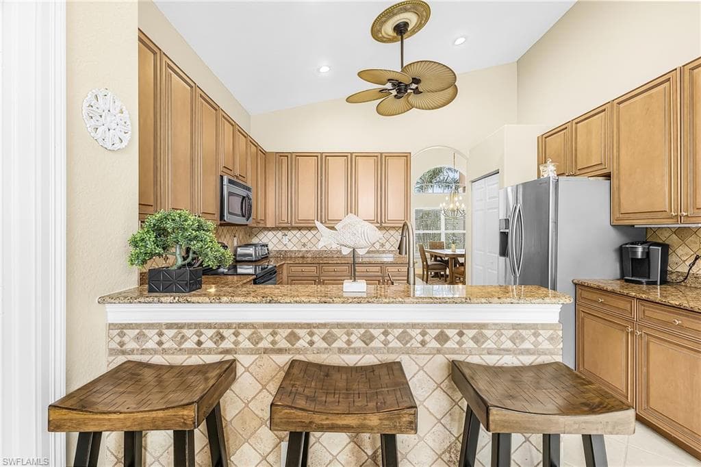 Kitchen featuring wood-finish cabinetry, granite countertops, stainless steel appliances, and a tiled backsplash