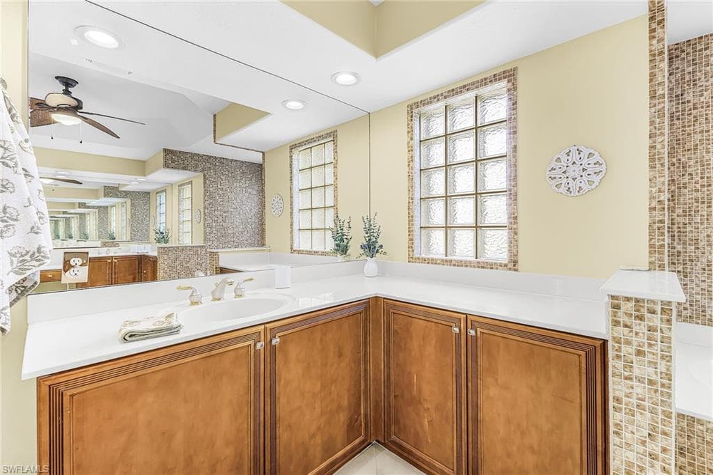 Recessed lighting, wood-finish cabinetry, white countertop, integrated sink, and glass block window