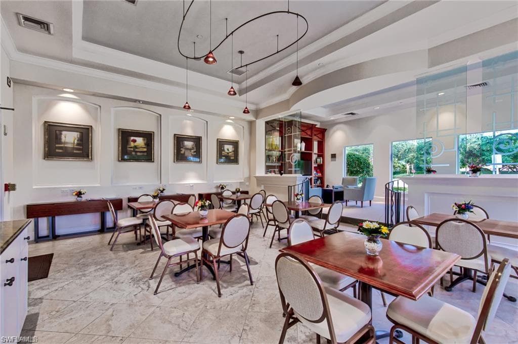 Spacious interior featuring patterned tile flooring, a coved ceiling, recessed lighting, track lighting, and multiple windows