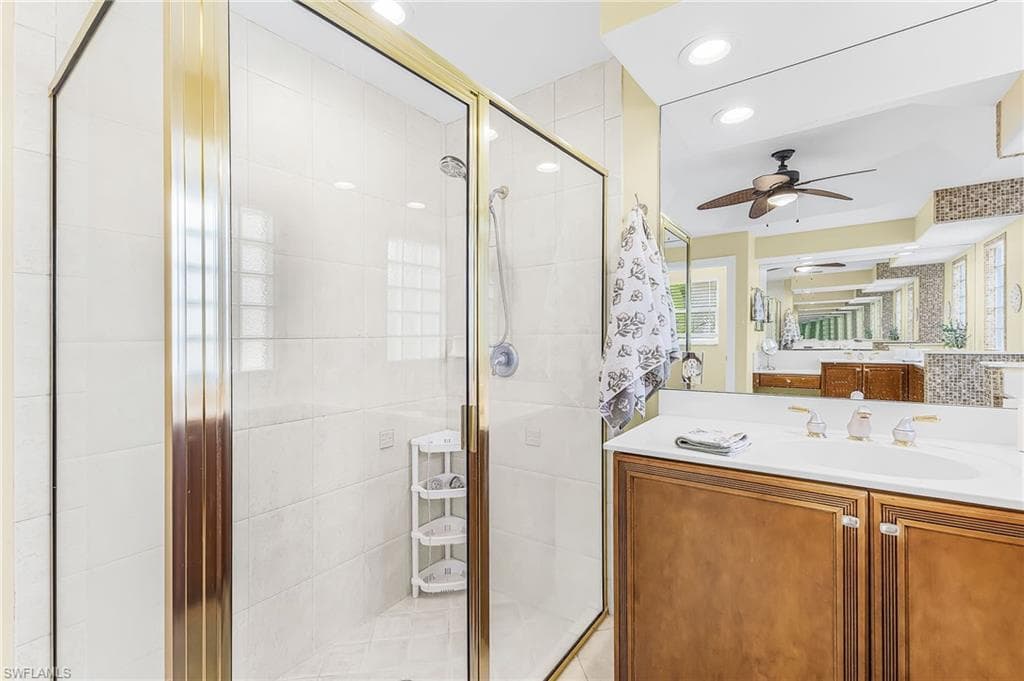 Glass-enclosed shower with gold-tone framing and white tile surround