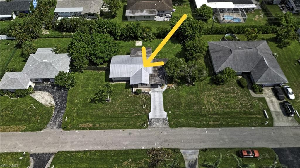 Single-story residence featuring a metal roof, concrete driveway, and surrounding green space