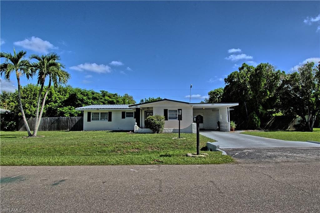 Single-story residence featuring a carport, mature palm trees, and a concrete driveway