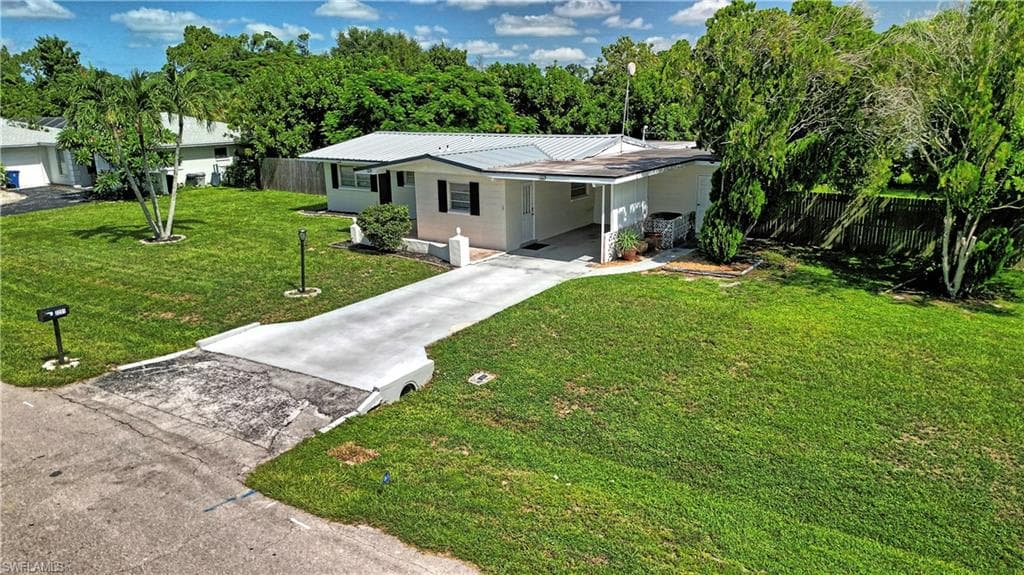 Single-story residence featuring a metal roof, white exterior siding, and a covered carport