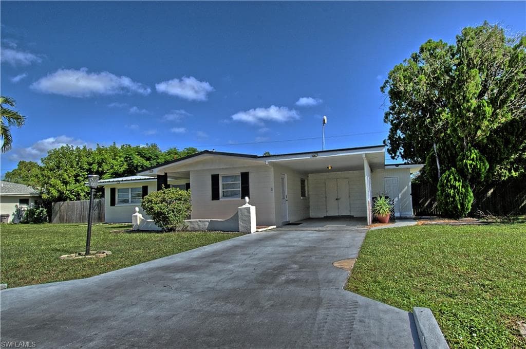 Contemporary exterior with a carport, concrete driveway, and established landscaping