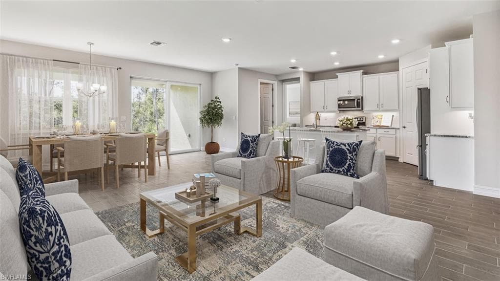 This image is virtually staged. Living room featuring wood finish floors and a chandelier