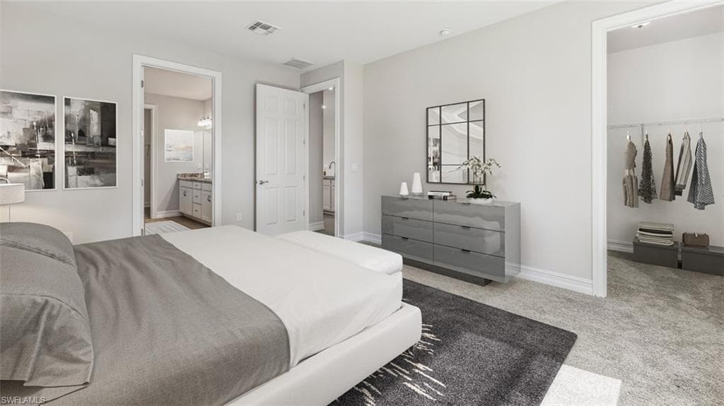 This image is virtually staged. Bedroom with light carpet, a walk in closet, and ensuite bathroom