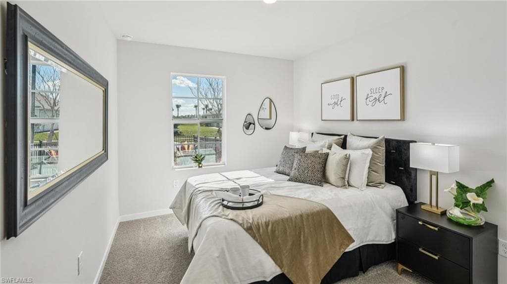 Bright bedroom featuring a large window, plush carpet flooring, and a contemporary wall mirror