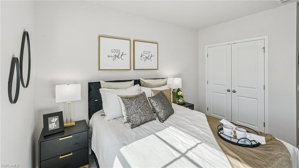 Bedroom with light-toned walls, a dark upholstered headboard, and dual panel closet doors