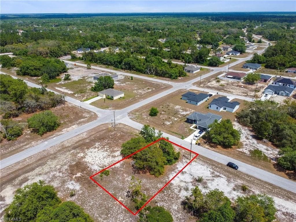 Residential lot with established neighborhood setting, surrounded by mature trees and paved roads