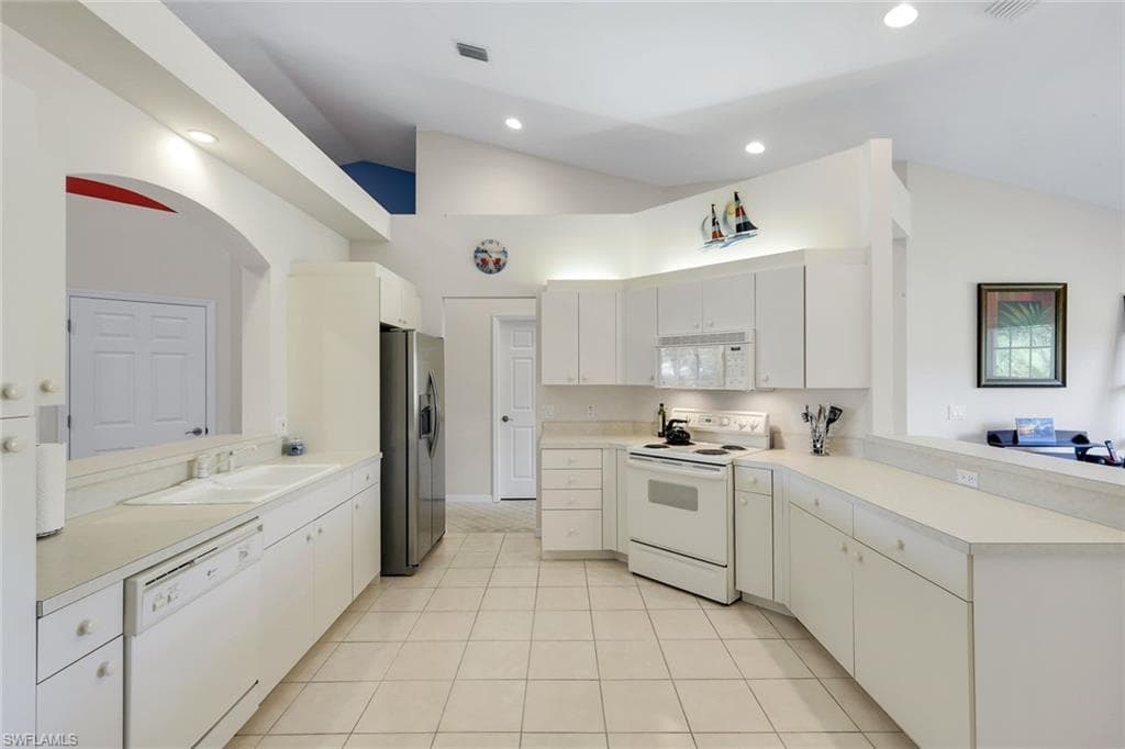 Bright Kitchen with Ample Counter Space, White Cabinetry, Breakfast Bar, and Recessed Lighting