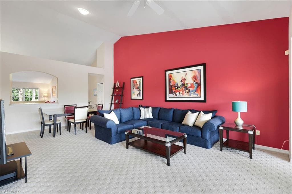 Inviting Living and Dining Areas Featuring a Vaulted Ceiling, Arched Pass-Through, Recessed Lighting, Ceiling Fan, Accent Wall, and Patterned Carpeting